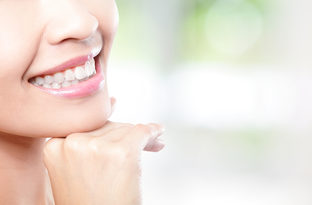 close up of woman with dental crown smiling and resting her chin on her hand