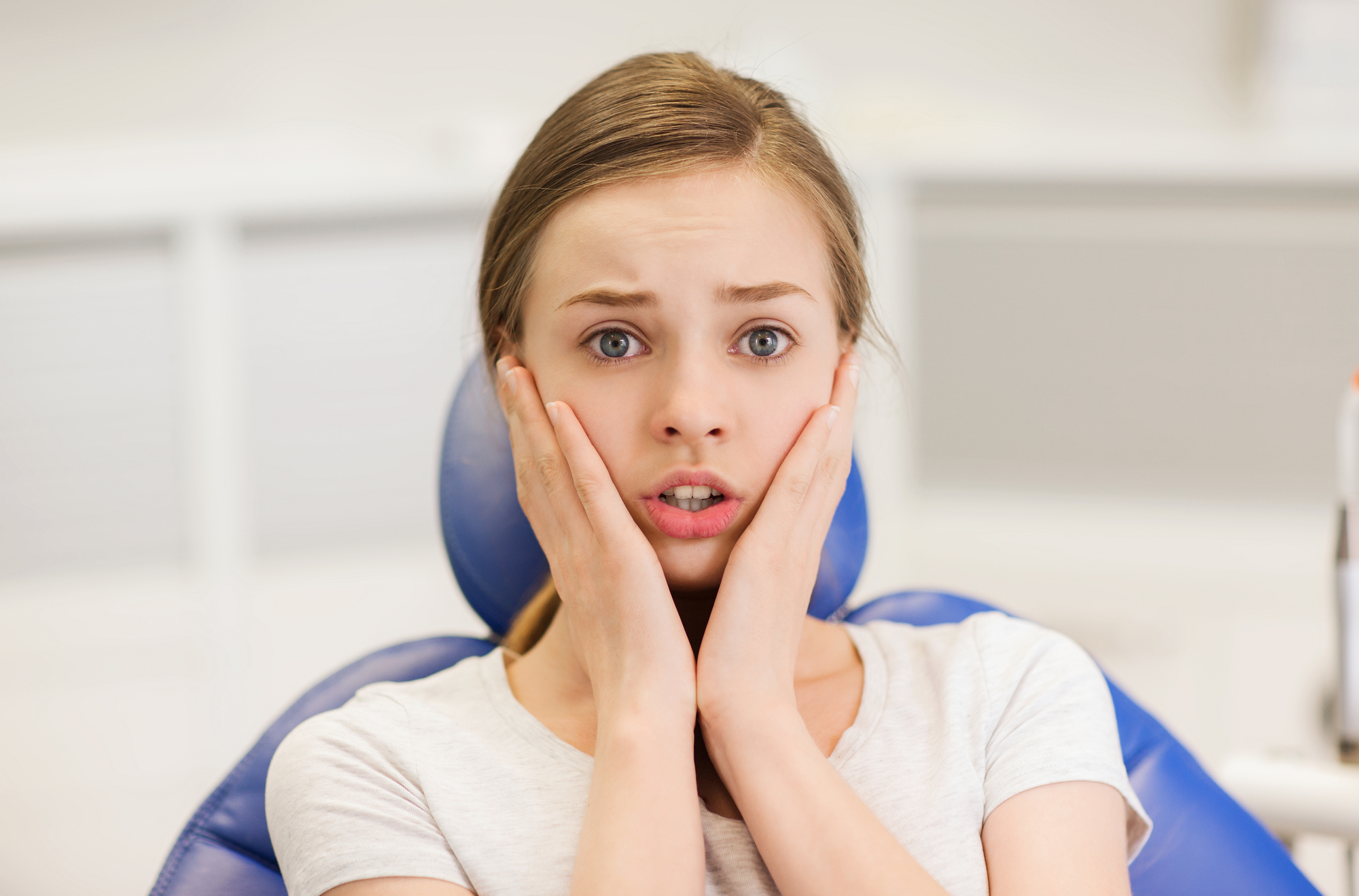 Scared young woman sits in a dental chair
