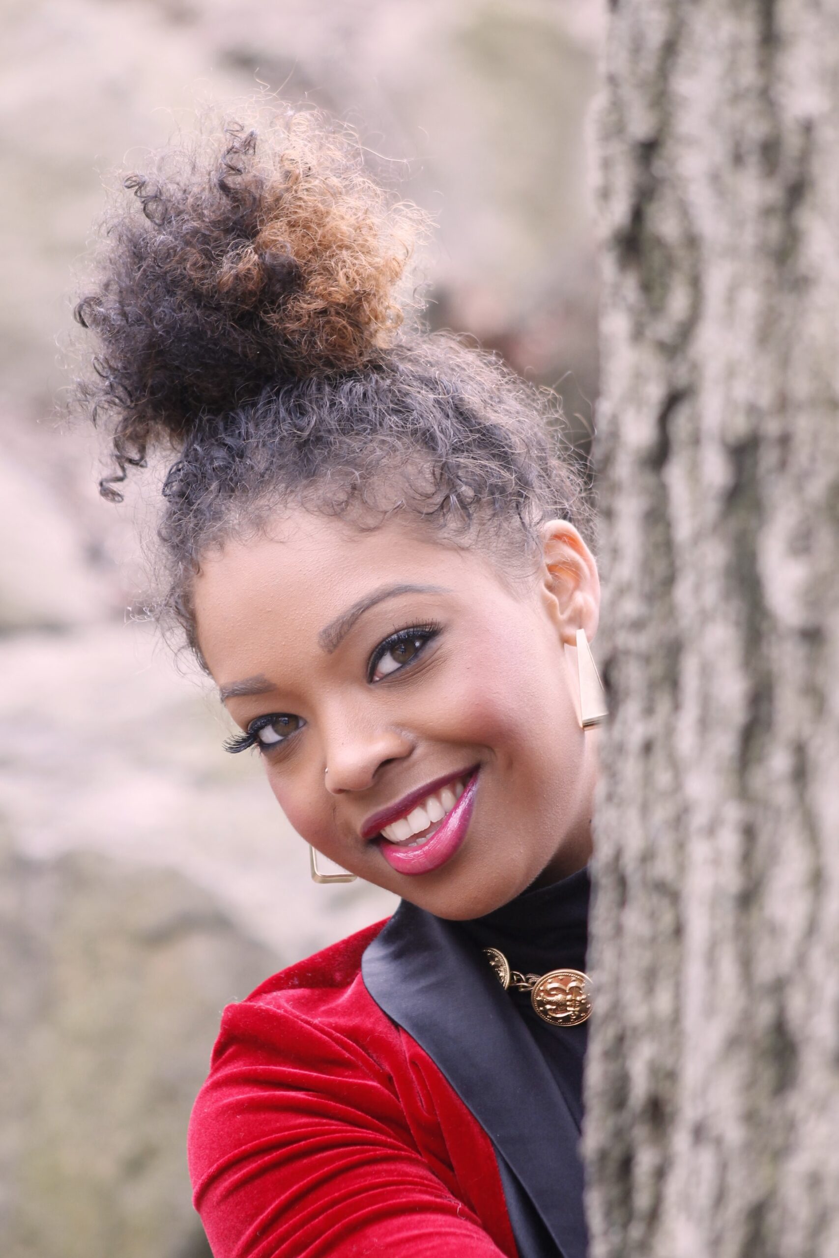young black woman smiling from behind a tree