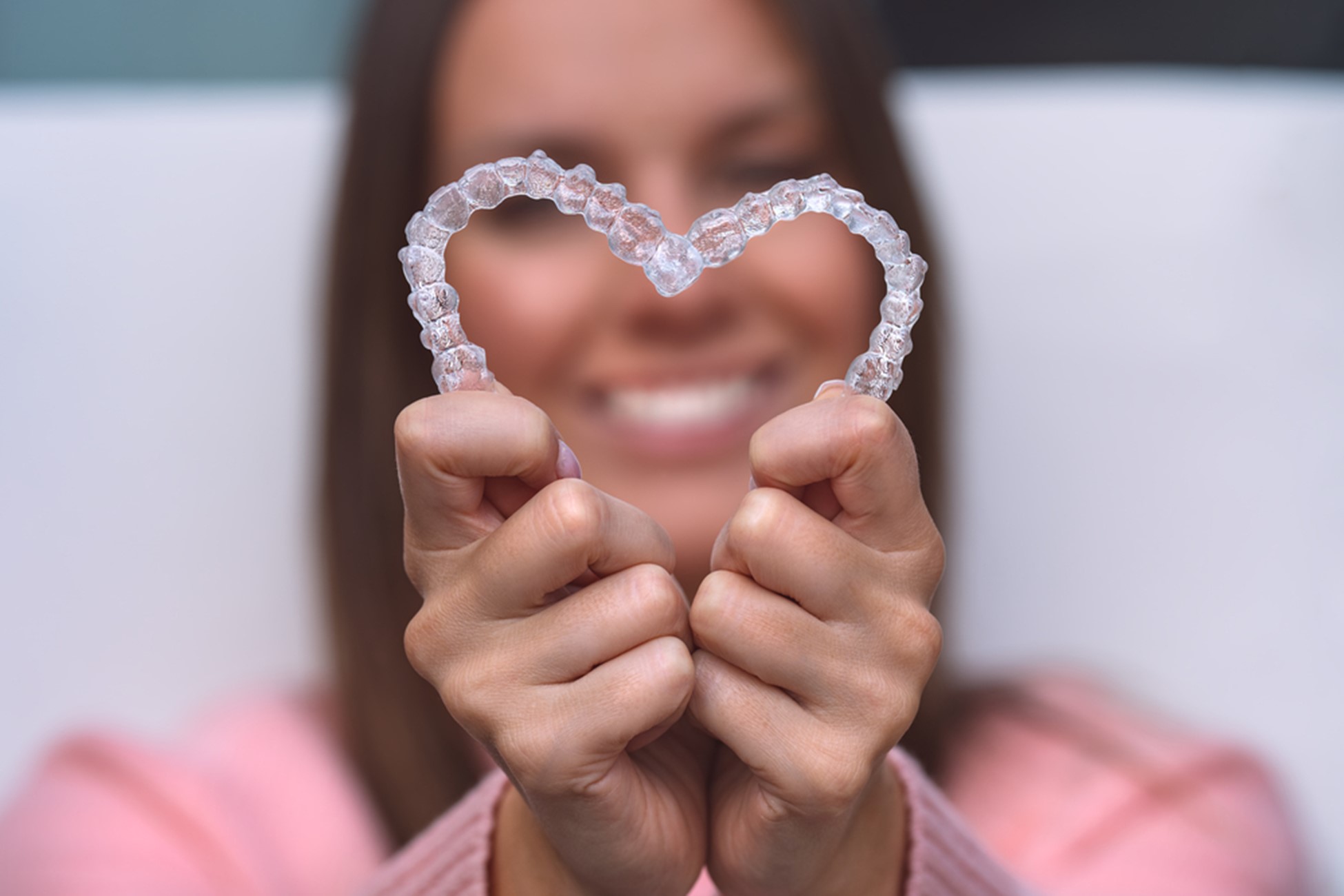 woman holding invisalign clear aligners in heart shape