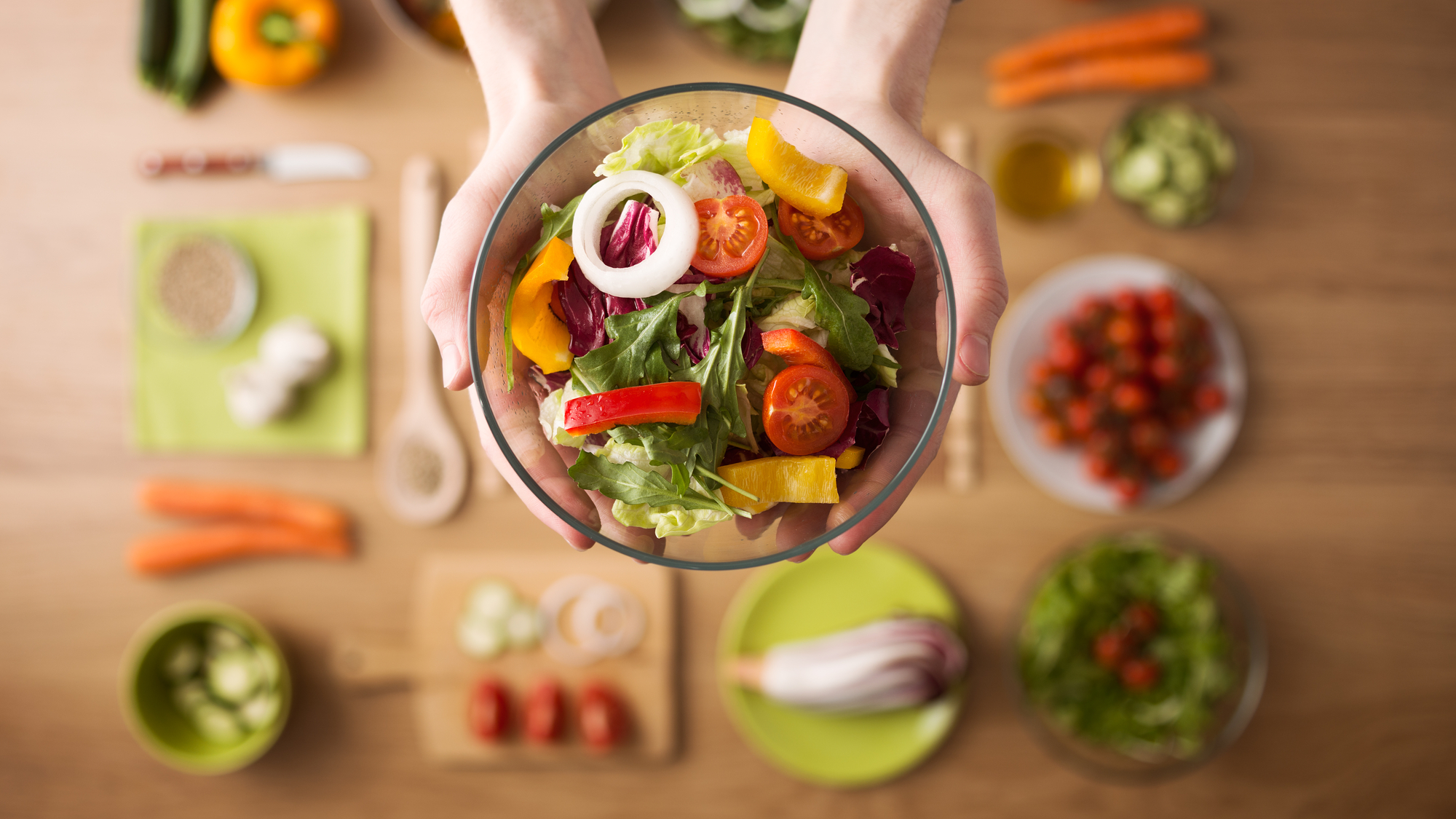 woman holding a bowl of food over a countertop full of ingredients