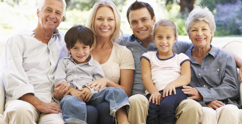 Three Generation Family Sitting On Sofa At Home