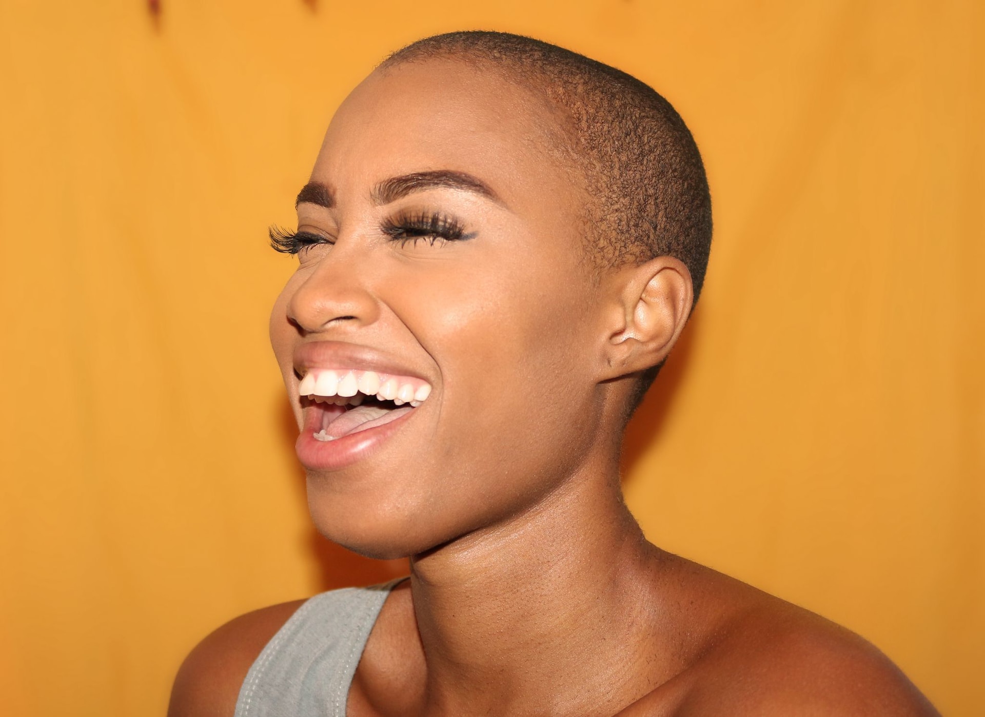 black woman laughing on orange background