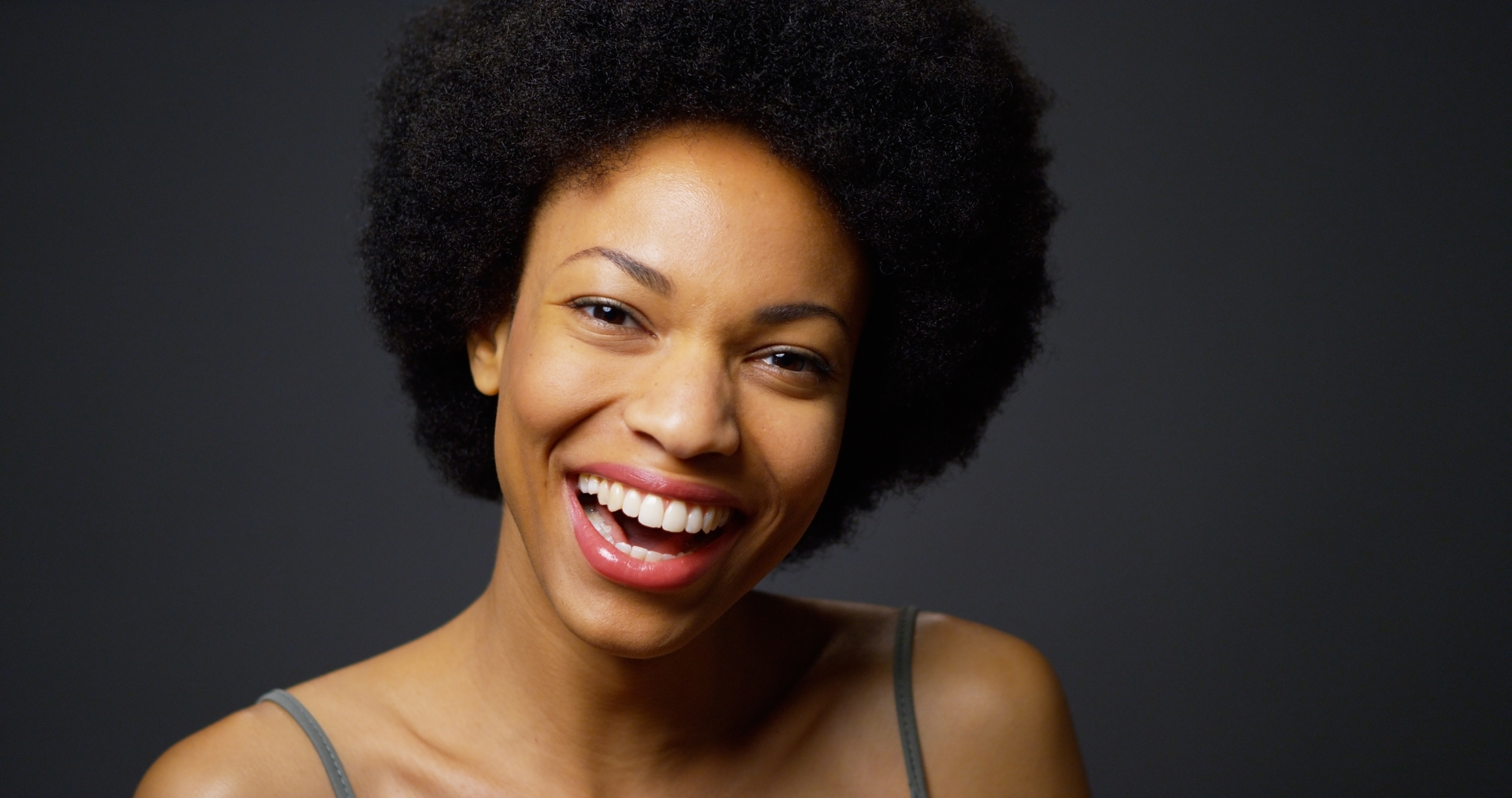black woman laughing on grey background