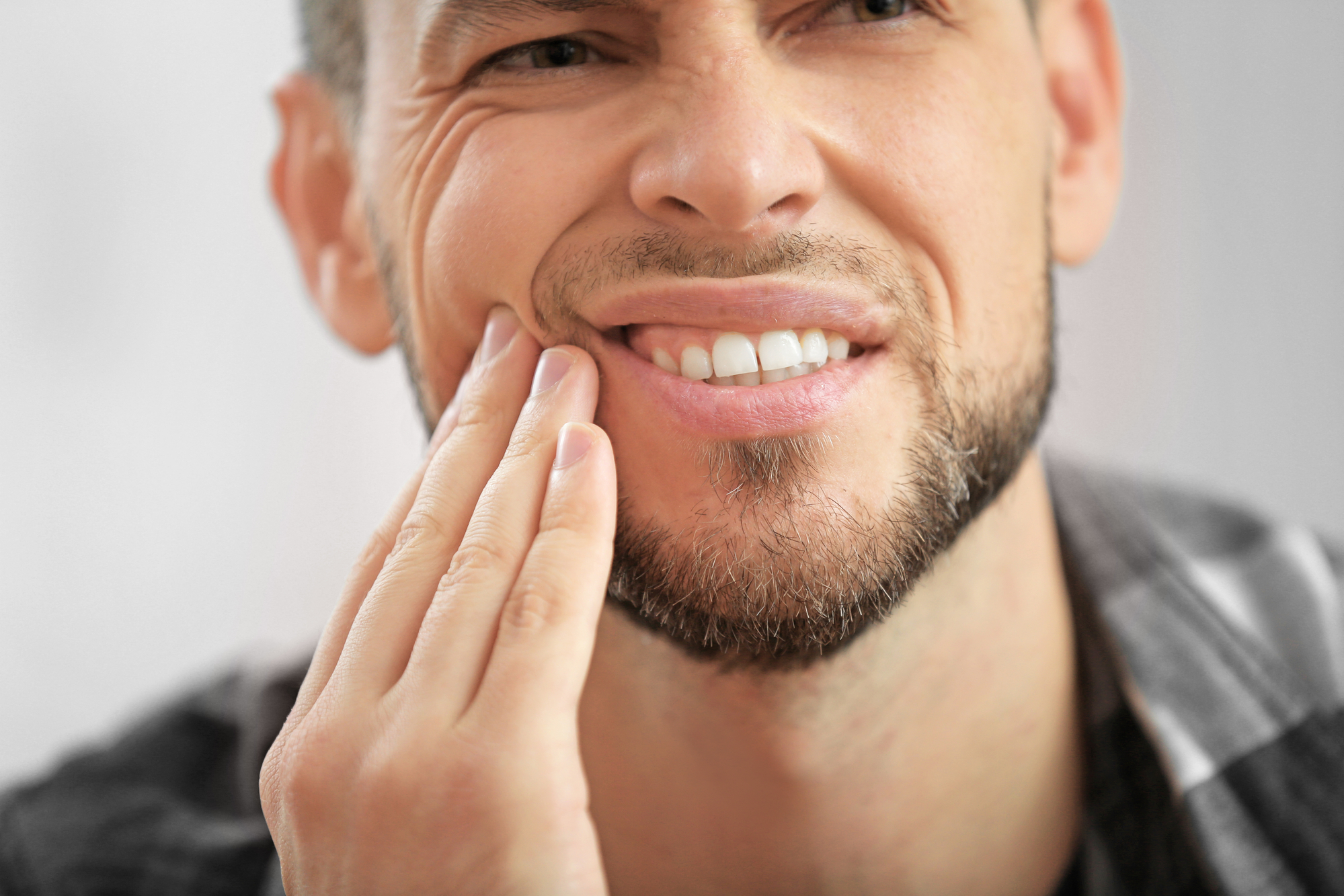 Handsome young man suffering from toothache, closeup