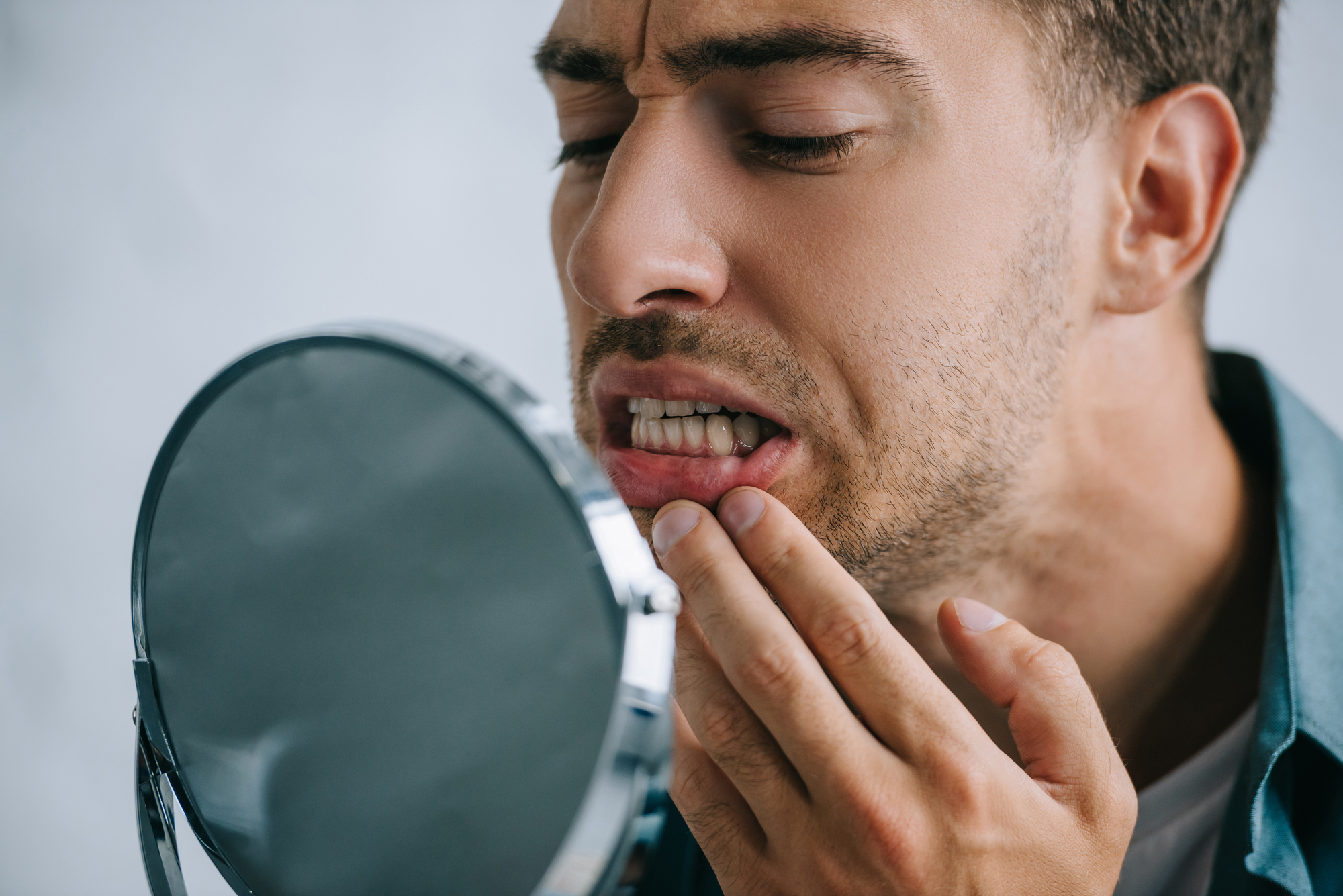 worried man looking in mirror at teeth and gums