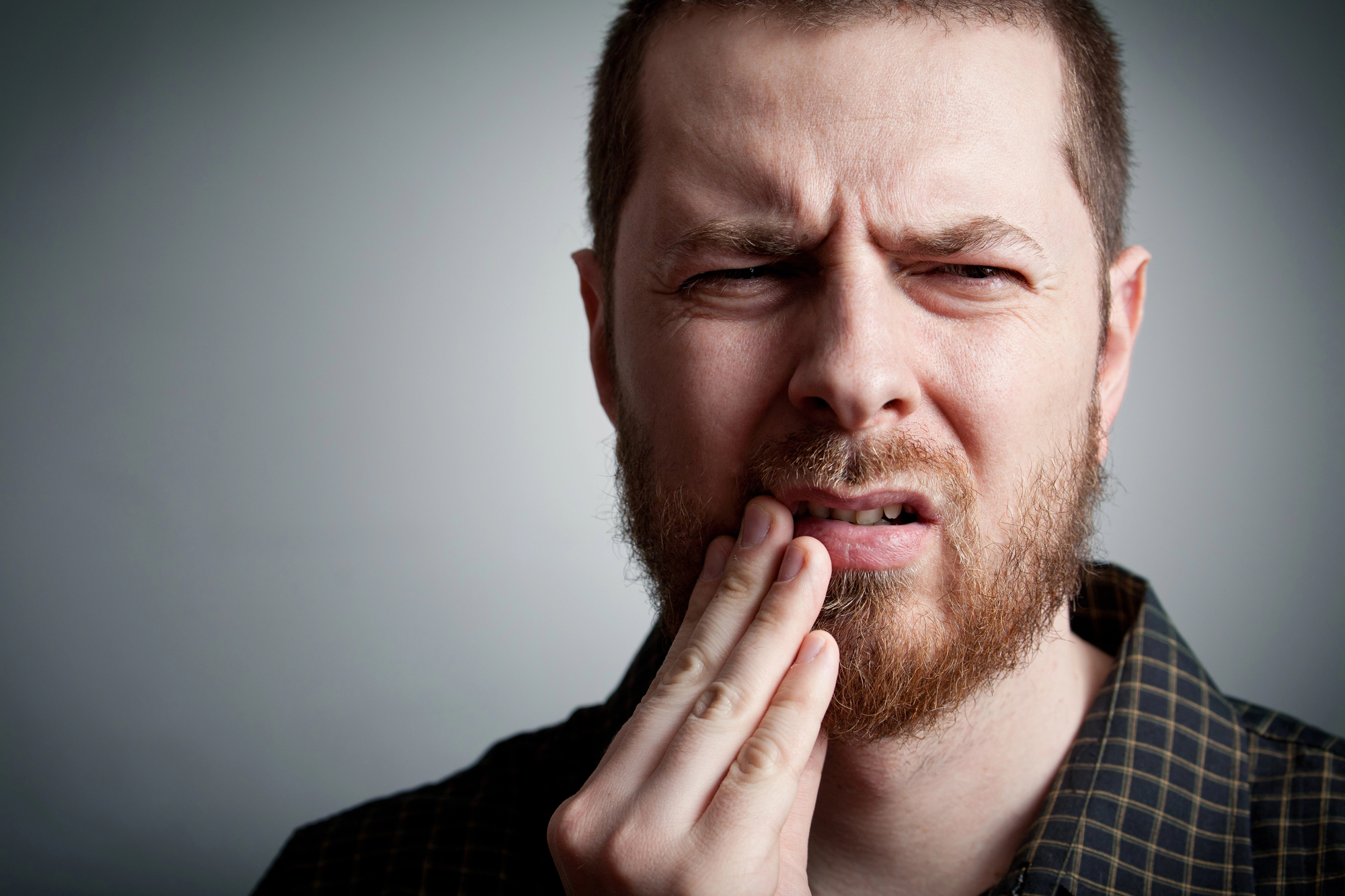 man touching his tooth because of toothache emergency