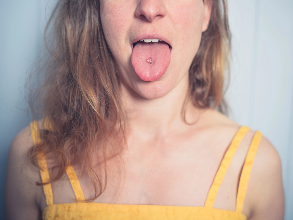 woman with oral piercings, sticking out tongue