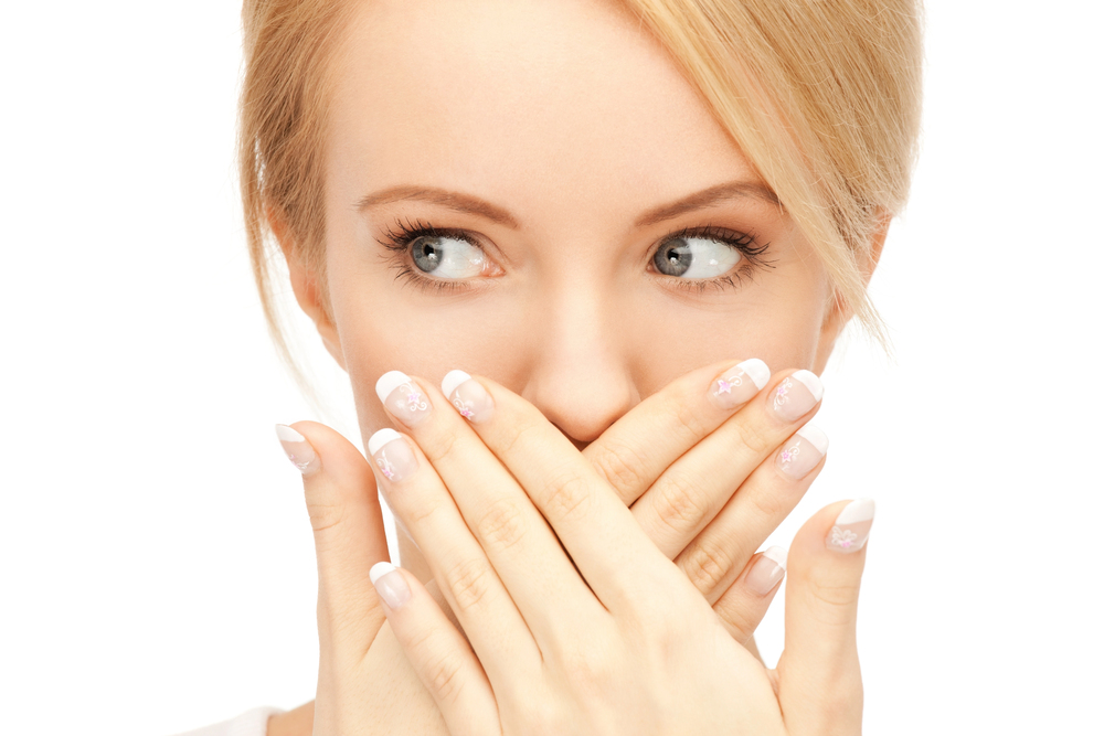 blonde woman covering her mouth with her hands