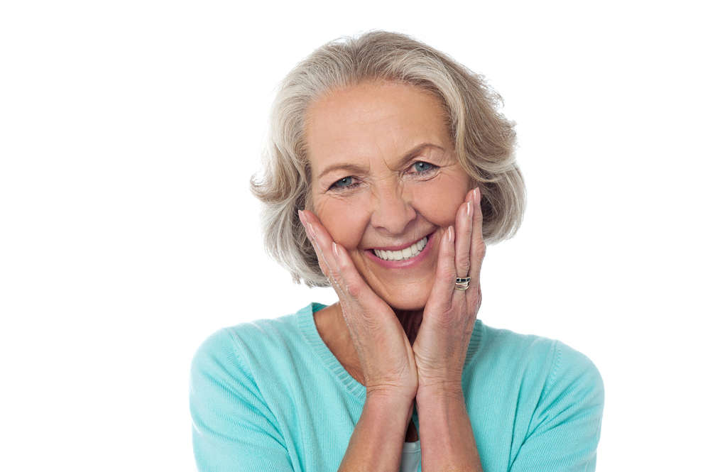 older woman holding her hands to her face in blue shirt